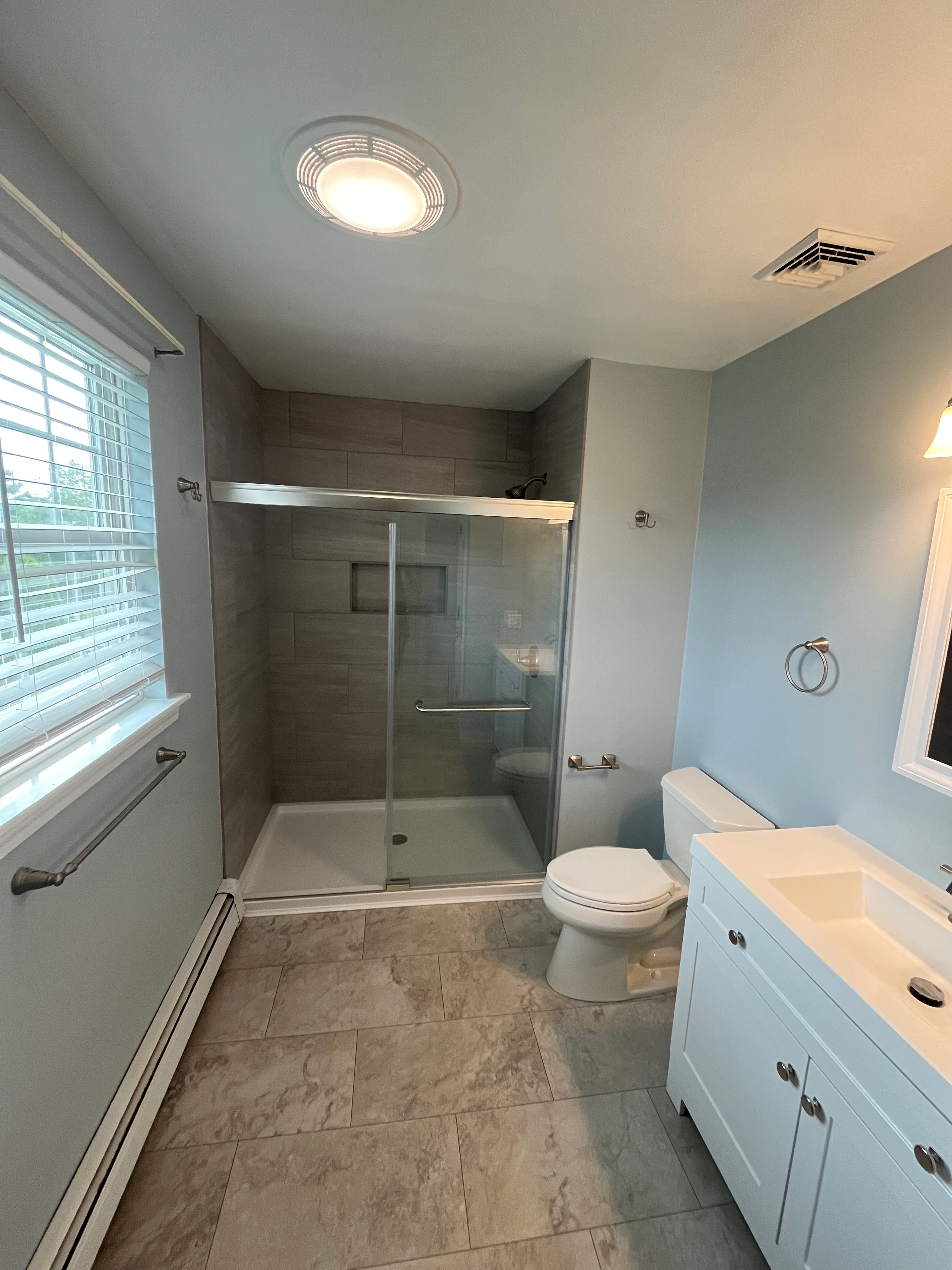 Completed primary bathroom with blue vanity and white subway tile