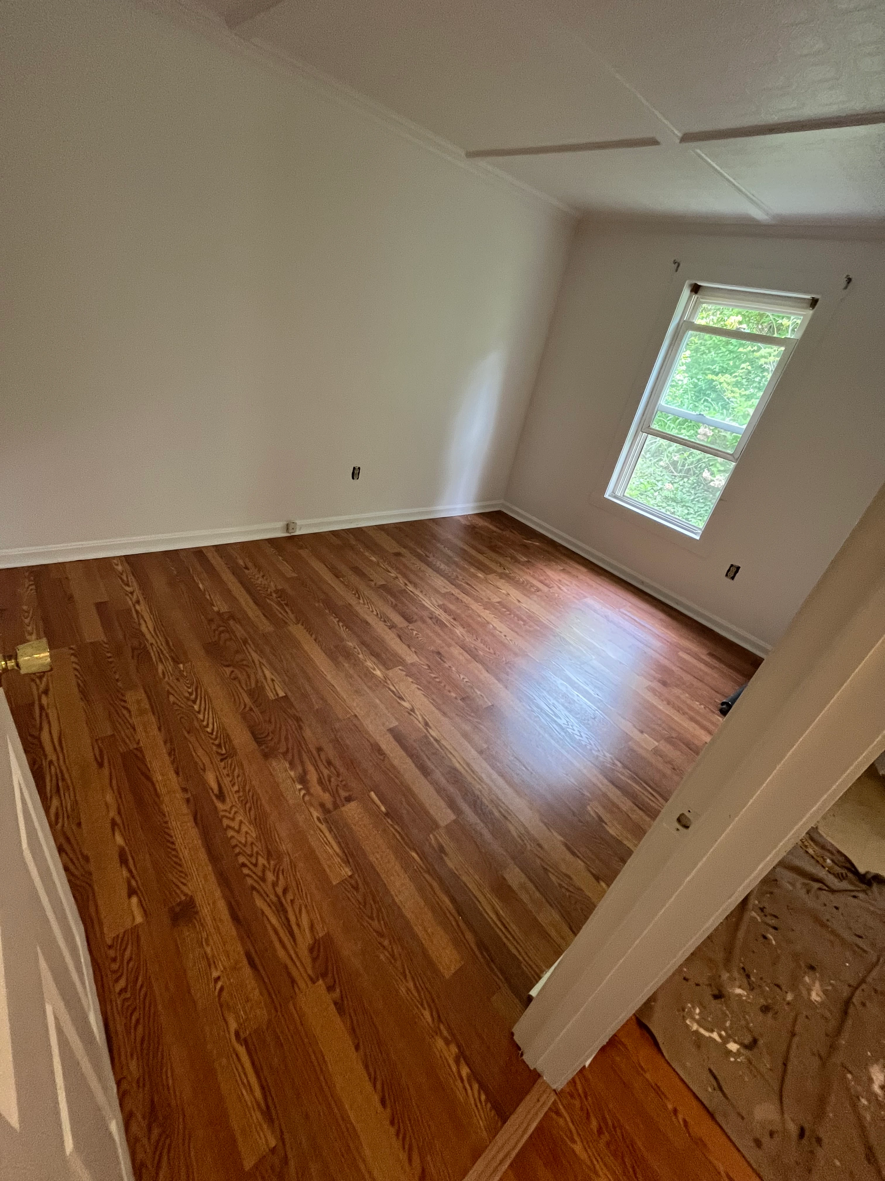 Refinished white oak hardwood flooring in a renovated bedroom