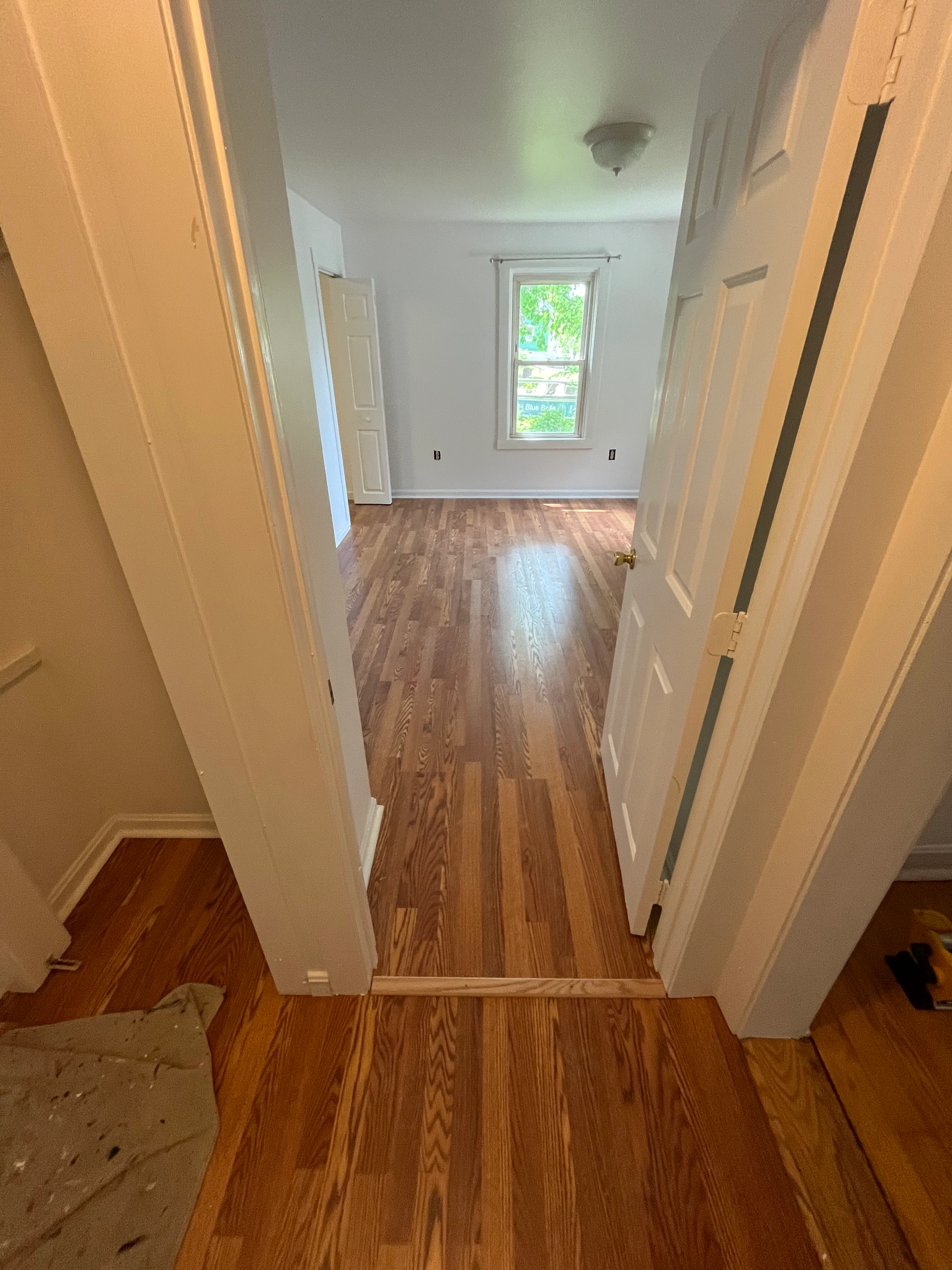 Refinished hardwood hallway leading to the renovated bathroom
