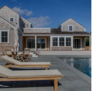 Pool lounge area with teak chairs and cedar-shake outbuilding