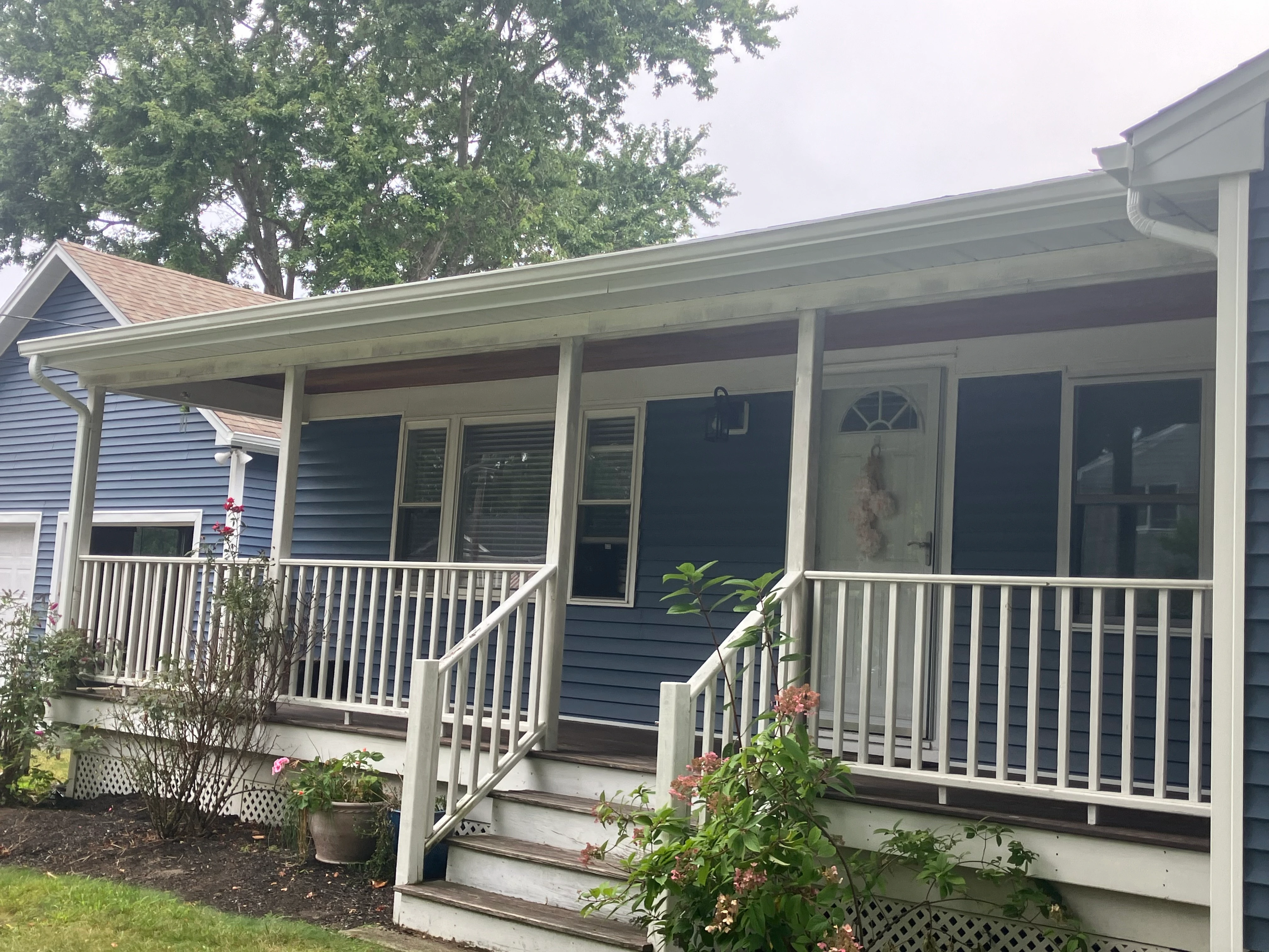 Front elevation of a West Warwick home with original worn white siding